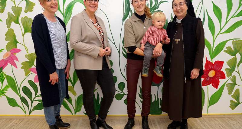 Das große Wandgemälde im Eingangsbereich ist schon fertig. Auf die Eröffnung des Kinderhauses „Kleine Freunde“ im Januar freuen sich (v.l.): Diana Ahlers, Elke Michaelis, Marlen Karthaus, hier mit Kind, und Schwester M. Angela Benoit. Foto: Michael Bodin / fcjm-presse