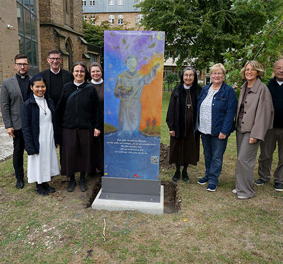 Aufstellung der Glasstele für den Pilgerradweg zum Sonnengesang des heiligen Franz von Assisi am Mutterhaus der Franziskanerinnen Salzkotten (v.l.): Michael Vockel-Böhmer (Glasmalerei Peters), Dechant Daniel Jardzejewski (Dekanat Büren-Delbrück), Schwester M. Francine Simamora (Franziskanerinnen), Pfarrer Martin Beisler (Pastoralverbund Salzkotten), Schwester Dr. M. Alexandra Völzke, Schwester M. Alexa Furmaniak, Schwester M. Angela Benoit (Franziskanerinnen Salzkotten), Marita Münsterteicher (Dekanat Büren-Delbrück), Ursula Schrader (Dekanat Büren-Delbrück), Pastor i.R. Uwe Schläger und Pastor i.R. Peter Gede (beide Vorbereitungskreis). Foto: Michael Bodin / fcjm-presse