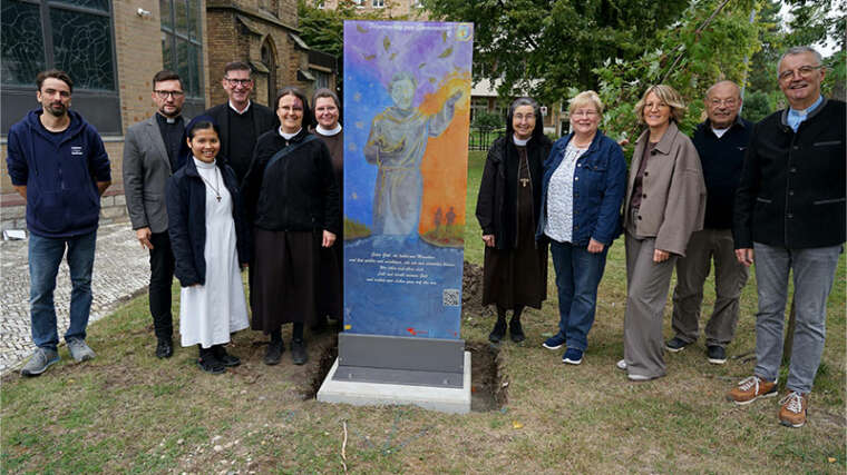 Aufstellung der Glasstele für den Pilgerradweg zum Sonnengesang des heiligen Franz von Assisi am Mutterhaus der Franziskanerinnen Salzkotten (v.l.): Michael Vockel-Böhmer (Glasmalerei Peters), Dechant Daniel Jardzejewski (Dekanat Büren-Delbrück), Schwester M. Francine Simamora (Franziskanerinnen), Pfarrer Martin Beisler (Pastoralverbund Salzkotten), Schwester Dr. M. Alexandra Völzke, Schwester M. Alexa Furmaniak, Schwester M. Angela Benoit (Franziskanerinnen Salzkotten), Marita Münsterteicher (Dekanat Büren-Delbrück), Ursula Schrader (Dekanat Büren-Delbrück), Pastor i.R. Uwe Schläger und Pastor i.R. Peter Gede (beide Vorbereitungskreis). Foto: Michael Bodin / fcjm-presse